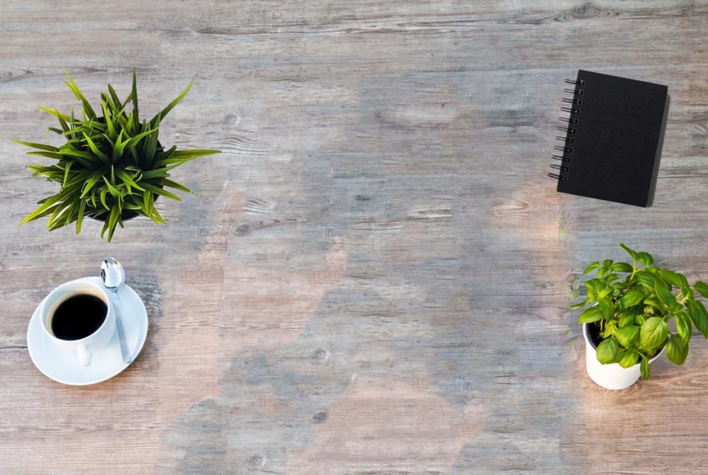 Top down view of a laptop, notepad, plants and a coffee. Charity Digital Marketing
